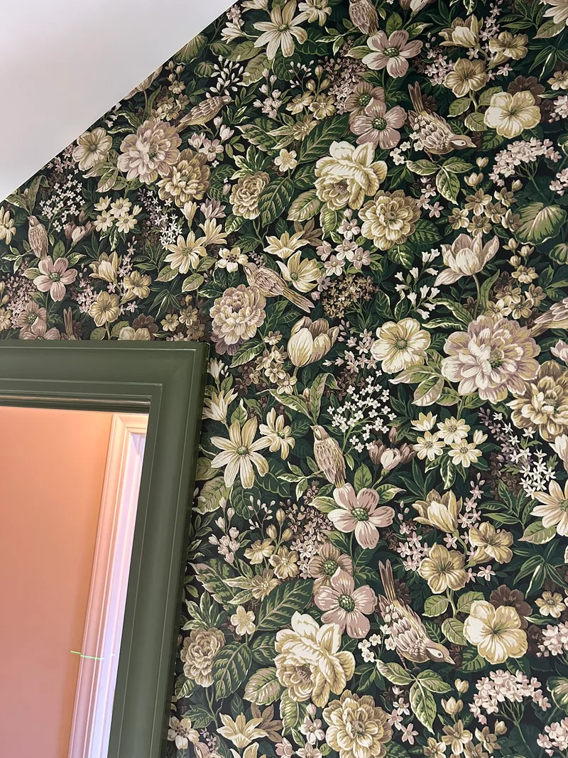 This luxurious Victorian powder room is enveloped in a rich, William Morris-inspired floral wallpaper featuring a dense, romantic pattern of large peonies, delicate anemones, tulips, and clusters of tiny white blossoms intertwined with lush green foliage and charming songbirds perched among the branches. Set against a deep forest green background, the creamy beiges, soft pinks, muted golds, and earthy browns create a timeless, garden-like opulence with exquisite detail and vintage charm. Perfect for bedrooms, sitting rooms, or any area craving immersive, nature-inspired elegance—this bold yet harmonious design transforms walls into a living work of art, evoking English countryside romance with sophisticated depth. (Installed to breathtaking effect in a local Easley-area home!)