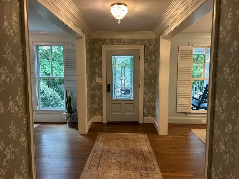 Elegant Foyer Transformation – Downtown Greenville, SC This charming foyer received a complete wallpaper transformation featuring a soft sage green background with delicate white floral and botanical patterns. The wallpaper was installed with precision around multiple doorways, windows, and detailed architectural trim for a seamless, high-end finish. The light, timeless design beautifully brightens the space while maintaining a classic Southern elegance that perfectly suits this historic downtown Greenville home. Another satisfied client project by Charles Benton Wallpapering.