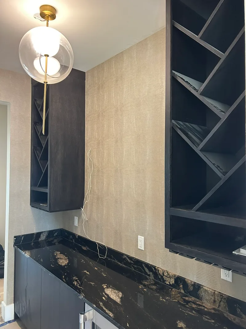 Embossed Alligator Print Bar Installation This sophisticated embossed alligator-print wallpaper adds rich texture and luxury to a high-end bar in a custom home build in the Five Forks area. The metallic neutral tone beautifully complements the black marble countertop, dark cabinetry, and modern geometric wine storage. Installed with precision around outlets, corners, and built-in cabinetry for a seamless, professional finish. Another standout project by Charles Benton Wallpapering — bringing bold textures and premium materials to custom homes in Upstate South Carolina.